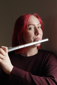 a woman with red hair holding a flute