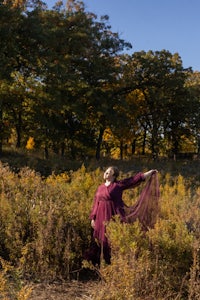 a woman in a purple dress standing in a field