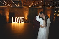 a bride and groom kiss in front of a love sign