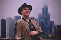 a man wearing a hat and a jacket in front of a city skyline