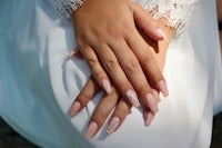 a woman wearing a white dress with pink nails