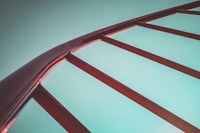 a close up of a red railing against a blue sky