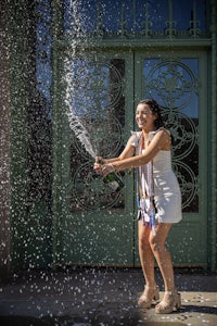 a woman in a white dress is spraying champagne