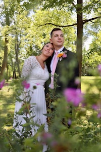 a bride and groom posing for a photo in the woods