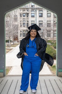 a woman in a blue gown standing in front of an archway