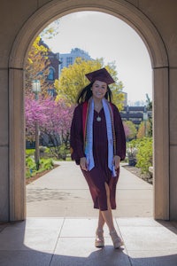 a woman in a graduation gown standing in an archway