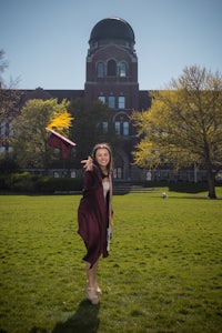 a woman in a graduation gown posing in front of a building