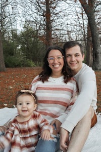 a family sits on a blanket in a park