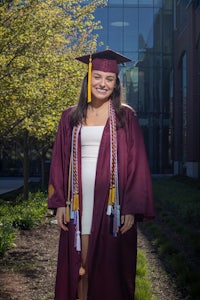 a woman in a graduation gown standing in front of a building