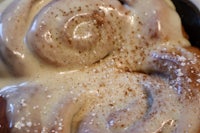 a close up of a cinnamon roll with powdered sugar