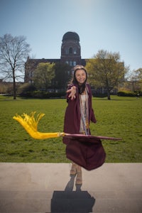 a woman in a graduation gown holding a yellow wand