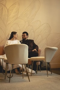 a bride and groom sitting on chairs in a room