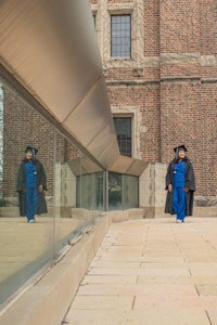 a person in a graduation gown standing in front of a brick building