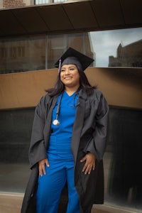 a woman in a graduation gown posing in front of a building