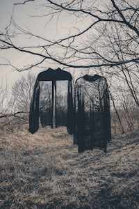 two black jackets hanging on a tree in the woods